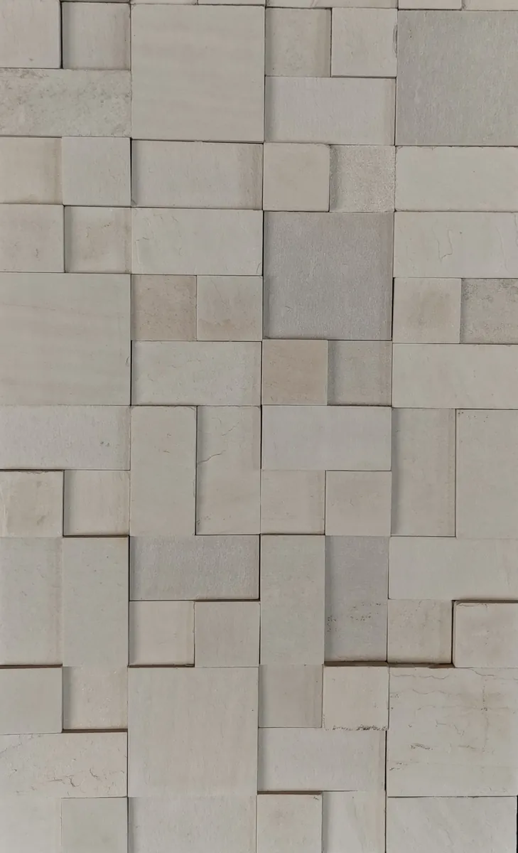 Amostra de Pedra Branca Mosaico. Peças claras em composição geométrica, com variação de profundidade.