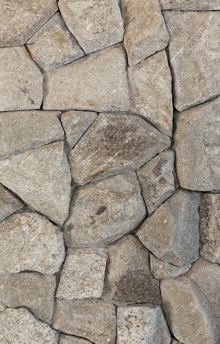 Amostra de Moledo. Pedras de contornos irregulares, com textura marcada e variações de tons neutros e terrosos.